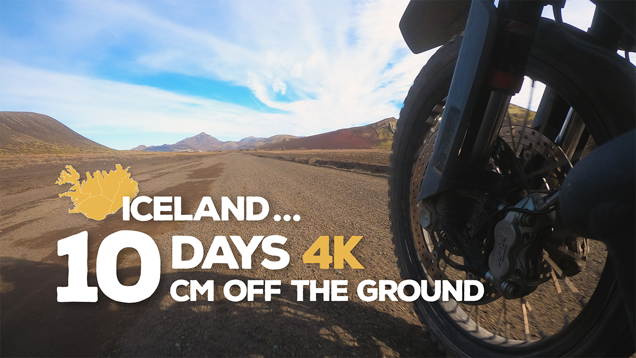 A view of a dirt road in Iceland from low down next to a motorcycle wheel.
