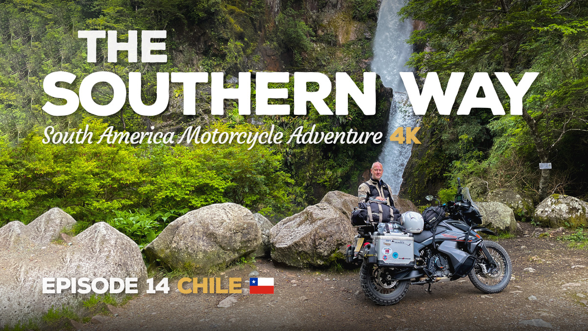 A photo of Benjamin Craig standing in front of a KTM 890 Adventure motorcycle in front of a waterfall in Chile.